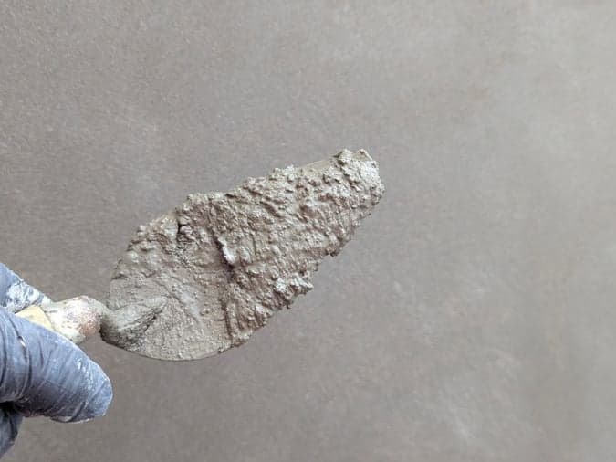 Taloche appliquant un enduit lissé sur un mur